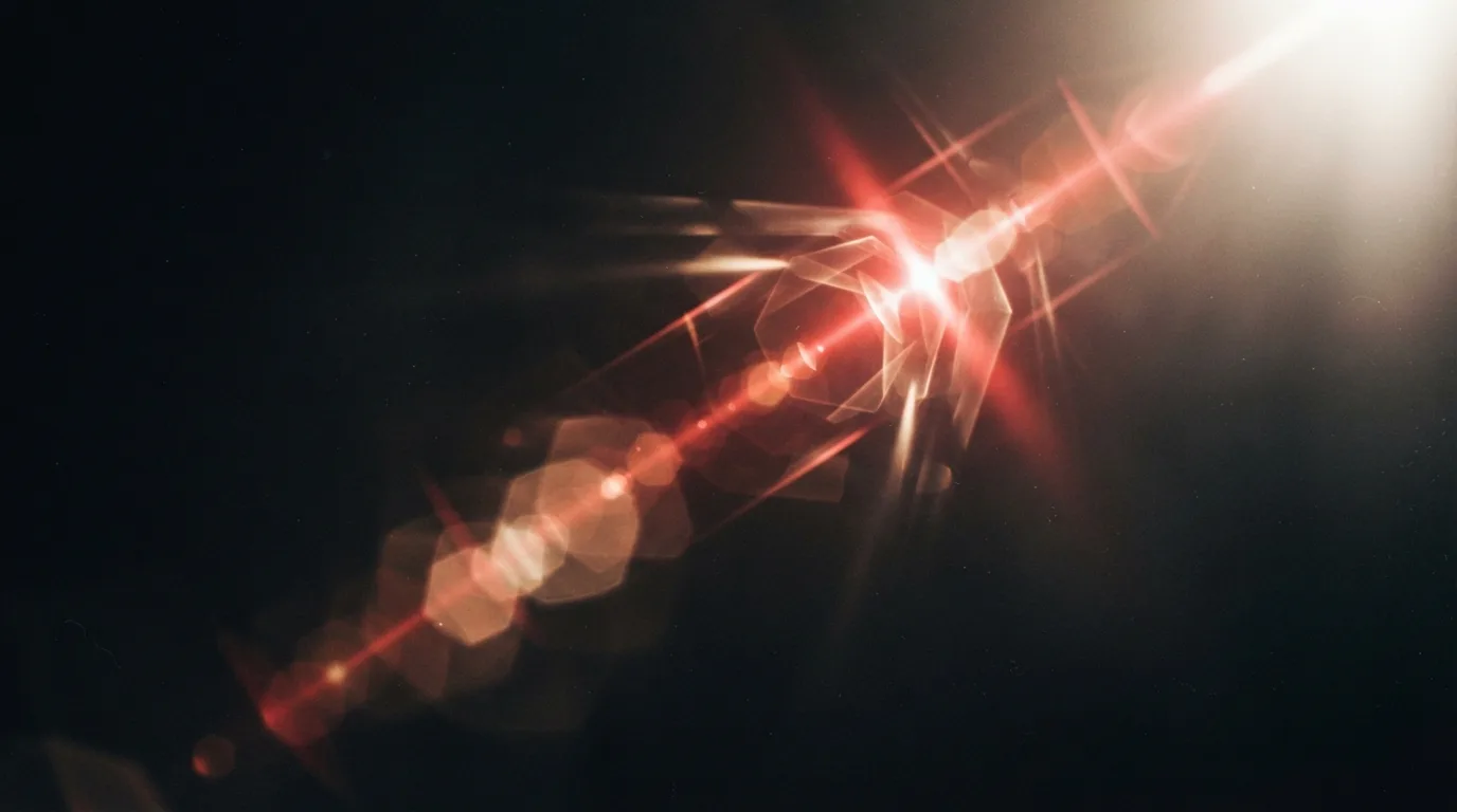 Abstract illustration of a red lens flare streaking across a dark camera lens