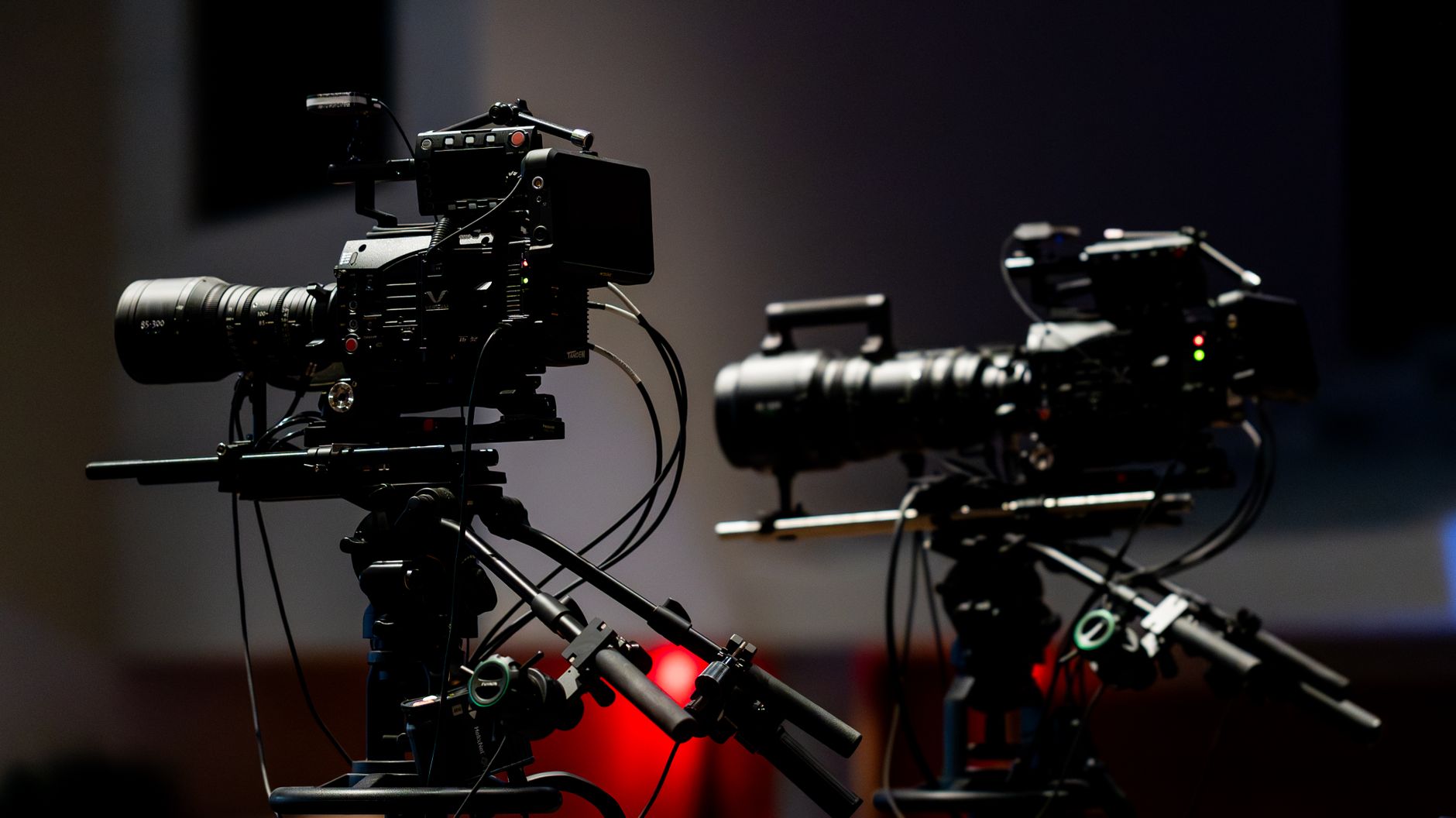 A cinema camera on a dark film set lit by a single practical light